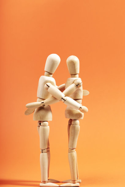 两个假人在橙色背景上互相拥抱。友谊的概念图片下载
