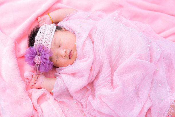 新生儿，特写漂亮的熟睡男婴。新生婴儿睡在毯子上，画面美丽，七天，新生婴儿戴大布，布玫瑰头带。图片下载