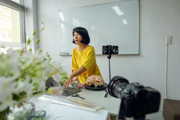 亚洲女花艺老师，小型企业花艺课程的老板，在线教授插花课程，使用智能手机，相机和笔记本电脑进行视频记录。电子学习，在线教程的概念图片下载