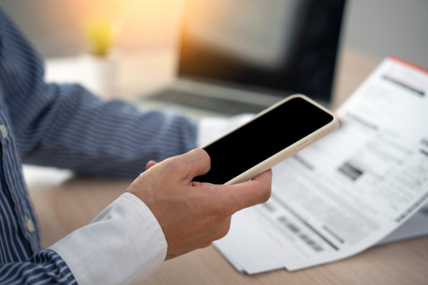 商人在收到发票后，用手机扫描条形码或二维码支付每月的信用卡账单。网上缴费概念图片下载