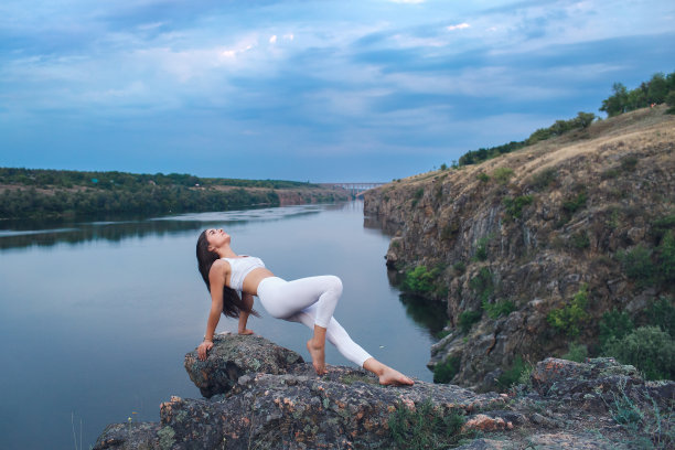 这个女孩正在做瑜伽，在岩石河岸上以平板支撑的姿势站立。图片下载