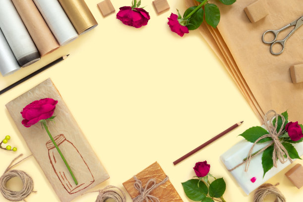 礼品在纸包装，一套复古的黄色包装纸，卷，绳和装饰铅笔。黄色复古背景上的一束红玫瑰图片下载