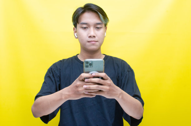 亚洲男子拿着手机用无线耳机听音乐图片下载