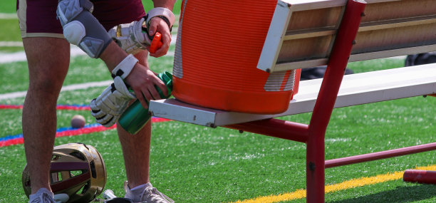 长曲棍球运动员在比赛期间从长凳上的冷却器中取水图片下载