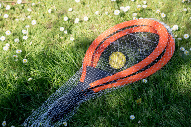 在一个阳光明媚的日子里，网球拍和球在绿色的场地上。美丽的光影对比和纹理。本空间图片下载