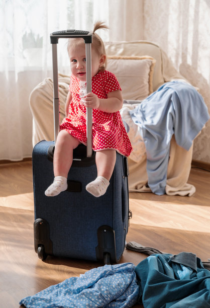 可爱的小女孩坐在行李箱上。和孩子一起旅行的概念。图片下载