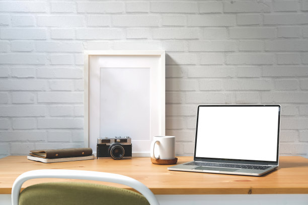 白色空屏的笔记本电脑，白色桌子上的相框、相机和咖啡杯。图片下载