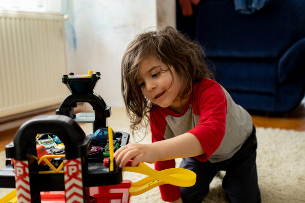 小男孩在家里的客厅里玩玩具汽车和停车场图片下载