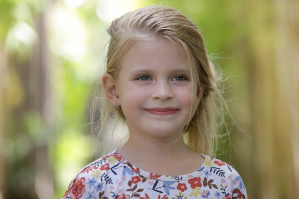 可爱的5岁女孩的户外偷拍照片，背景是绿色植物图片下载