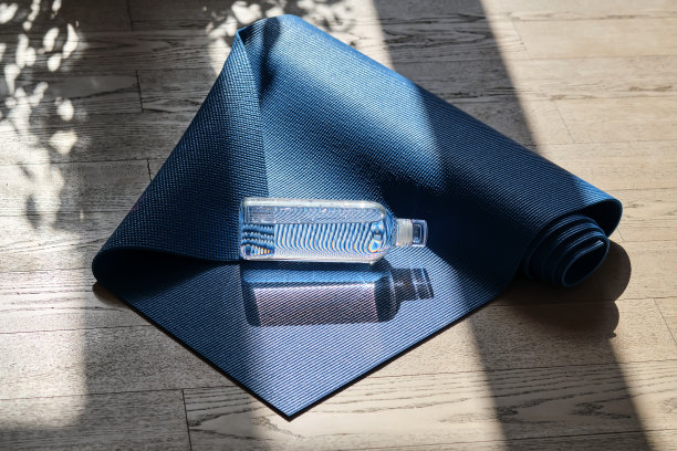 瑜伽垫上可重复使用的玻璃水瓶。图片下载