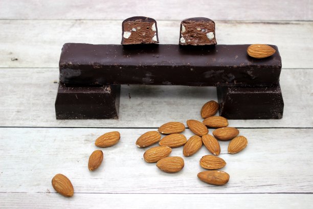 白色木制背景上的杏仁巧克力棒。图片下载