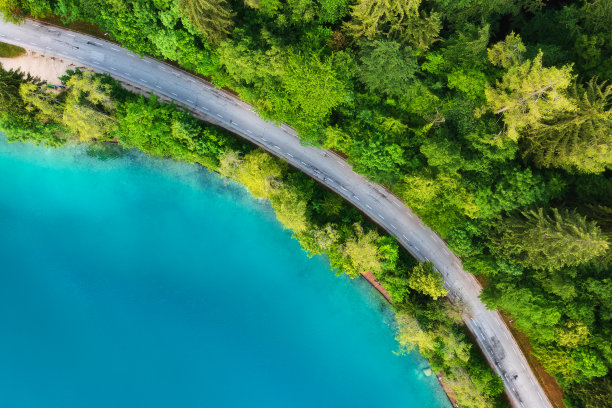 夏日日出时蓝色湖泊、绿色森林附近的鸟瞰图。布莱德湖，斯洛文尼亚。旅行。俯瞰美丽的道路，春天的树木。景观与公路和海湾。公路旅行。自然图片下载