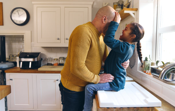 患有唐氏综合症的父亲和顽皮的儿子在厨房里微笑图片下载