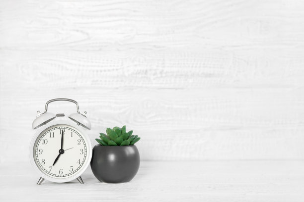 带闹钟、室内植物和复印空间的正面白色办公桌。早晨的背景横幅与文字的自由空间。极简主义的概念，工作空间，工作时间。空白的工作场所。办公室模型图片下载