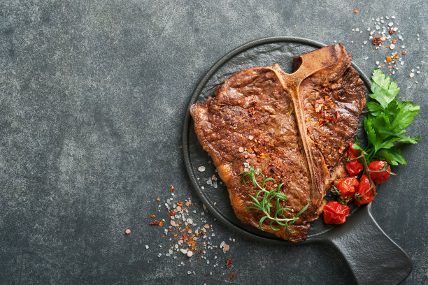 牛排丁字牛排。切片牛肉烤t骨或牛排肉牛排与香料迷迭香和胡椒黑色大理石板上的旧木背景。前视图。模拟。图片下载