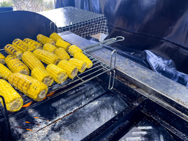 图片上的玉米棒烤在红色的木炭烧烤，这是一个美味的野餐菜。图片下载