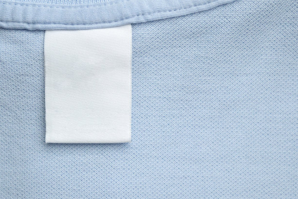 白色空白洗衣护理衣服标签在蓝色衬衫织物背景图片下载