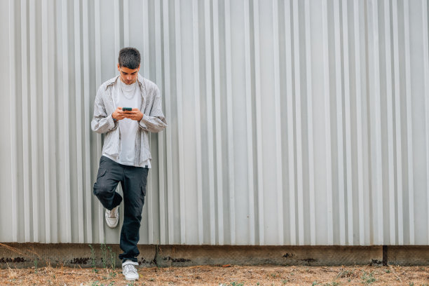 一个拿着手机站在街上的年轻人图片下载