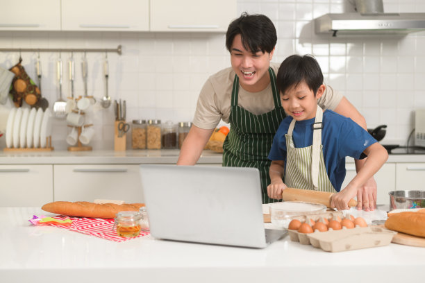 快乐微笑的年轻亚洲父子与母亲视频通话。享受在家厨房做饭的乐趣图片下载