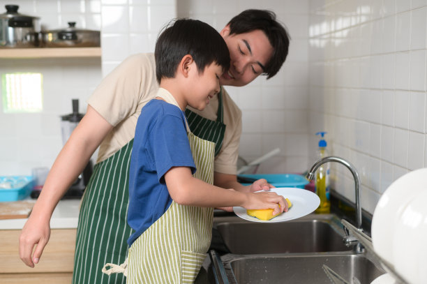 快乐微笑的年轻亚洲父亲和儿子在家里的厨房洗碗图片下载