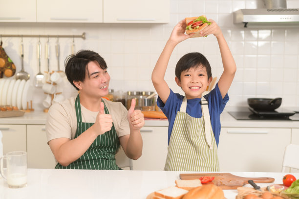 快乐的年轻亚洲父亲和儿子在家里的厨房吃健康的食物图片下载