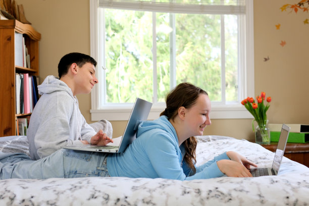 教育，人，科技，学习理念快乐的高中生在卧室使用笔记本电脑图片下载