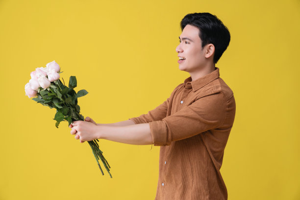 年轻的亚洲男子拿着花作为背景图片下载
