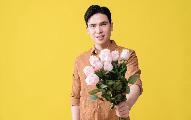 年轻的亚洲男子拿着花作为背景图片下载