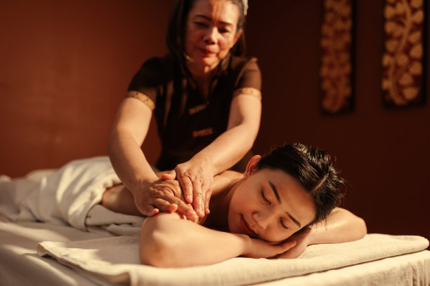 放松的亚洲女性顾客在水疗沙龙享受按摩师的芳香按摩服务。图片下载