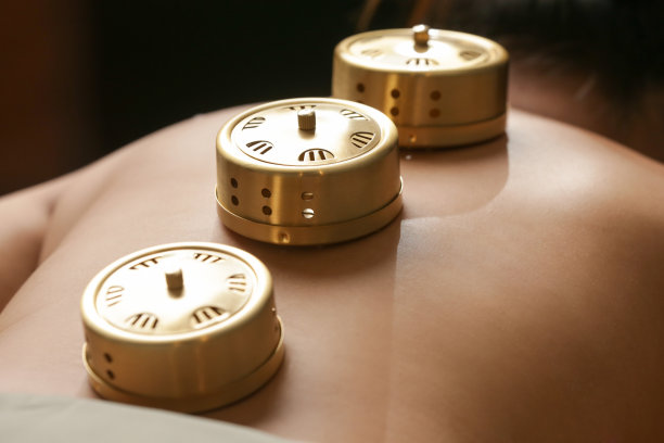 艾灸疗法——中医对穴位进行热疗的工具。艾灸铜燃烧器箱，用于妇女背部的温热按摩。中草药。图片下载