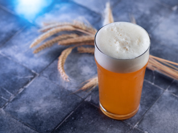一杯未经过滤的小麦啤酒放在蓝色瓷砖上，麦穗图片下载
