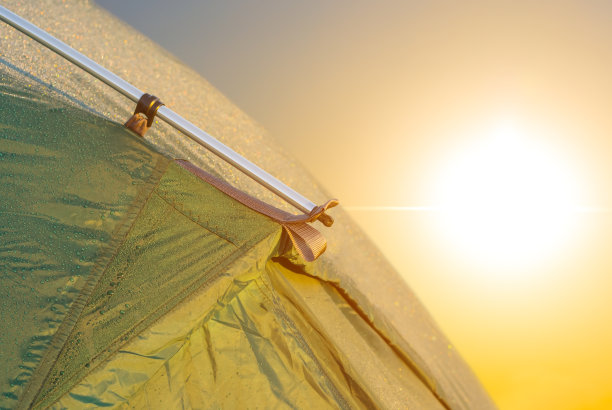 特写绿色旅游帐篷在傍晚的阳光下，旅行日落的背景图片下载