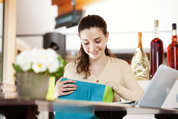 咖啡馆里一位美丽的年轻女子面带微笑，看着她那五颜六色的包里，她对自己买的东西和收到的礼物很满意图片下载