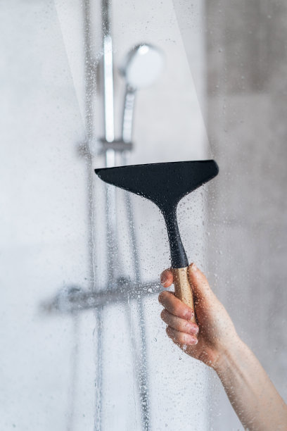 玻璃雨刷清洁淋浴隔墙上的污垢和水滴图片下载