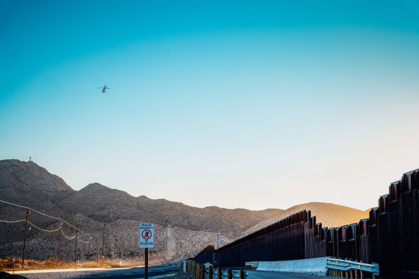 这张照片拍摄了德克萨斯州埃尔帕索和墨西哥华雷斯城之间的边界墙。宏伟的混凝土建筑将两座城市分隔开来，远处可以看到埃尔帕索的灯光。图片下载