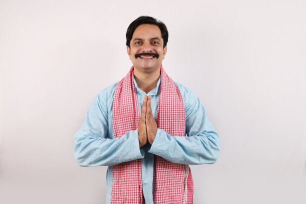 一幅美丽的肖像，一个年轻的中年男子站在一件蓝色的衬衫，微笑着看着相机，手折叠。图片下载