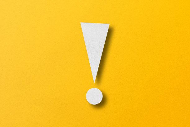 白纸打孔成感叹号的形状。警告标志设置在黄纸背景上图片下载