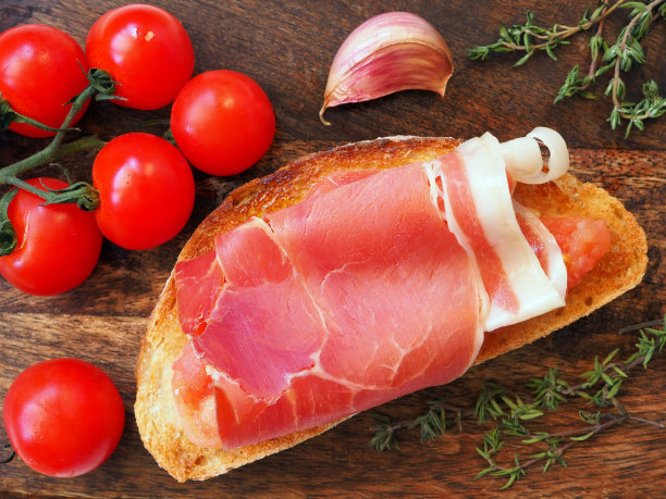 烤面包抹上新鲜的大蒜、白熟透的西红柿和火腿，然后淋上橄榄油图片下载
