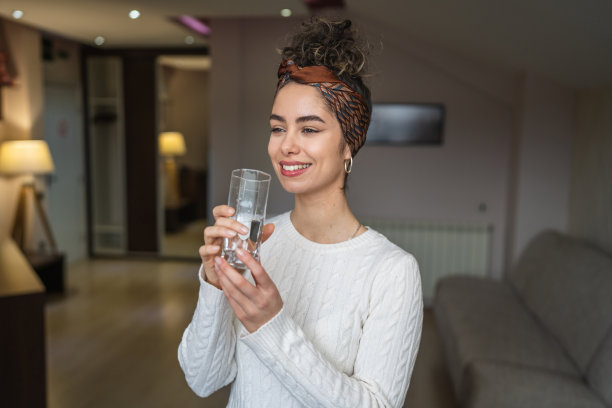 年轻的白人女性在家里喝一杯水图片下载