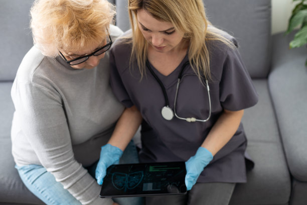 医生或护理人员手持平板电脑与家中或养老院的老年妇女图片下载