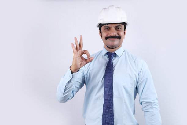 一位戴着白色工程师头盔的快乐印度工程师的画像。他很自信，竖起大拇指。图片下载