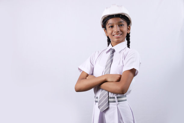 一个女学生的肖像和一个工程师的概念，手里拿着工程师头盔，白色的。她很自信，穿着校服。教育的概念。图片下载