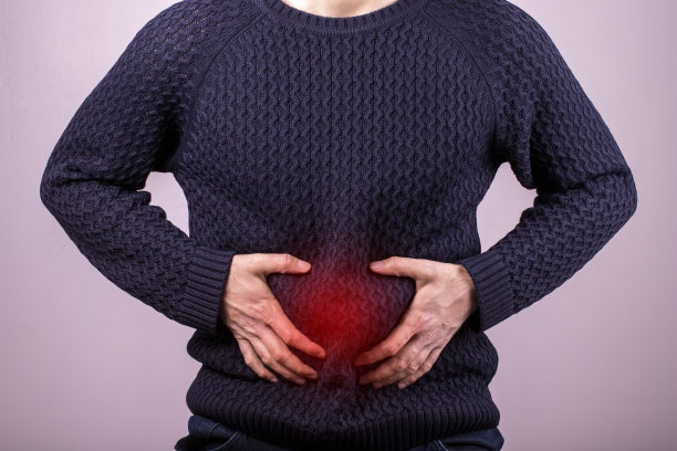 患有严重胃痛的男子坐在家里。患有疼痛、腹泻或消化不良问题的成年男子的手握住腹部。红色显示的疼痛区域图片下载