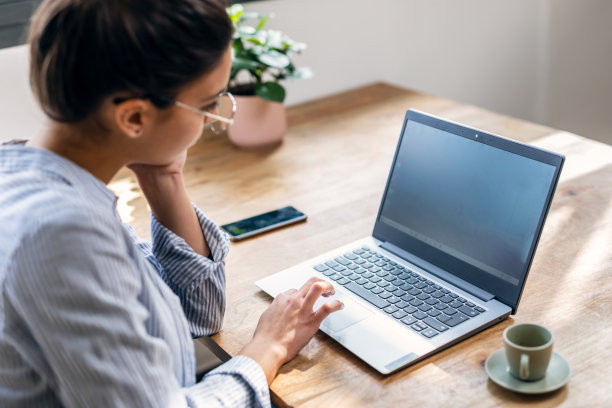 美丽迷人的女企业家一边在家里的客厅喝咖啡，一边用笔记本电脑工作。图片下载