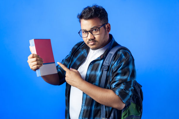 一个年轻的印度学生用手指着一本书。图片下载