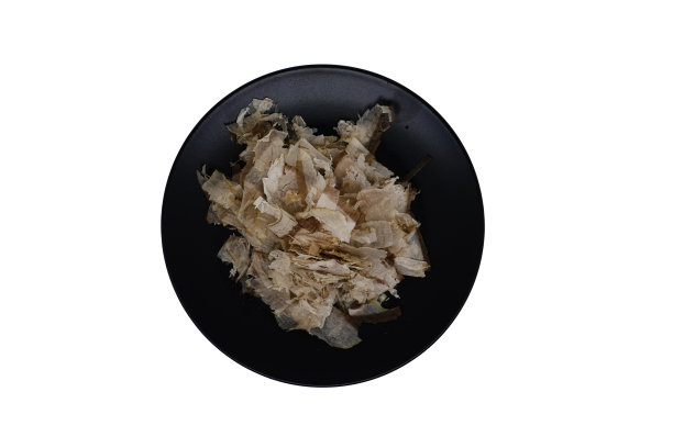 传统的日本食品，木鱼或干鲣鱼片在黑色盘子上，隔离在白色背景与复制空间。日式高汤的原料。俯视图或平面布局。图片下载