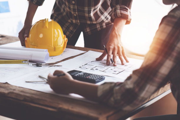 建筑师和工程师为建筑计划绘制蓝图，工程师为建筑项目绘制草图，绿色能源概念图片下载