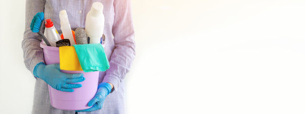 女性双手拿着装满不同清洁用品的水桶，特写。横幅。图片下载