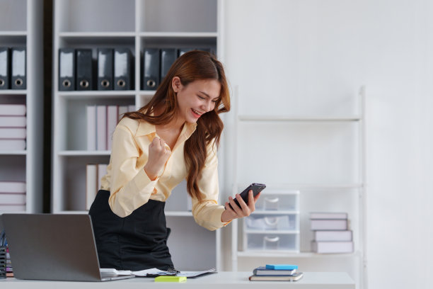 亚洲商人用手机庆祝胜利和成功，有好消息，工作庆祝成就。图片下载