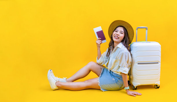 漂亮的亚洲女乘客拿着旅行和暑假的登机牌，带着黄色背景，带着复印空间，幸福地坐着图片下载
